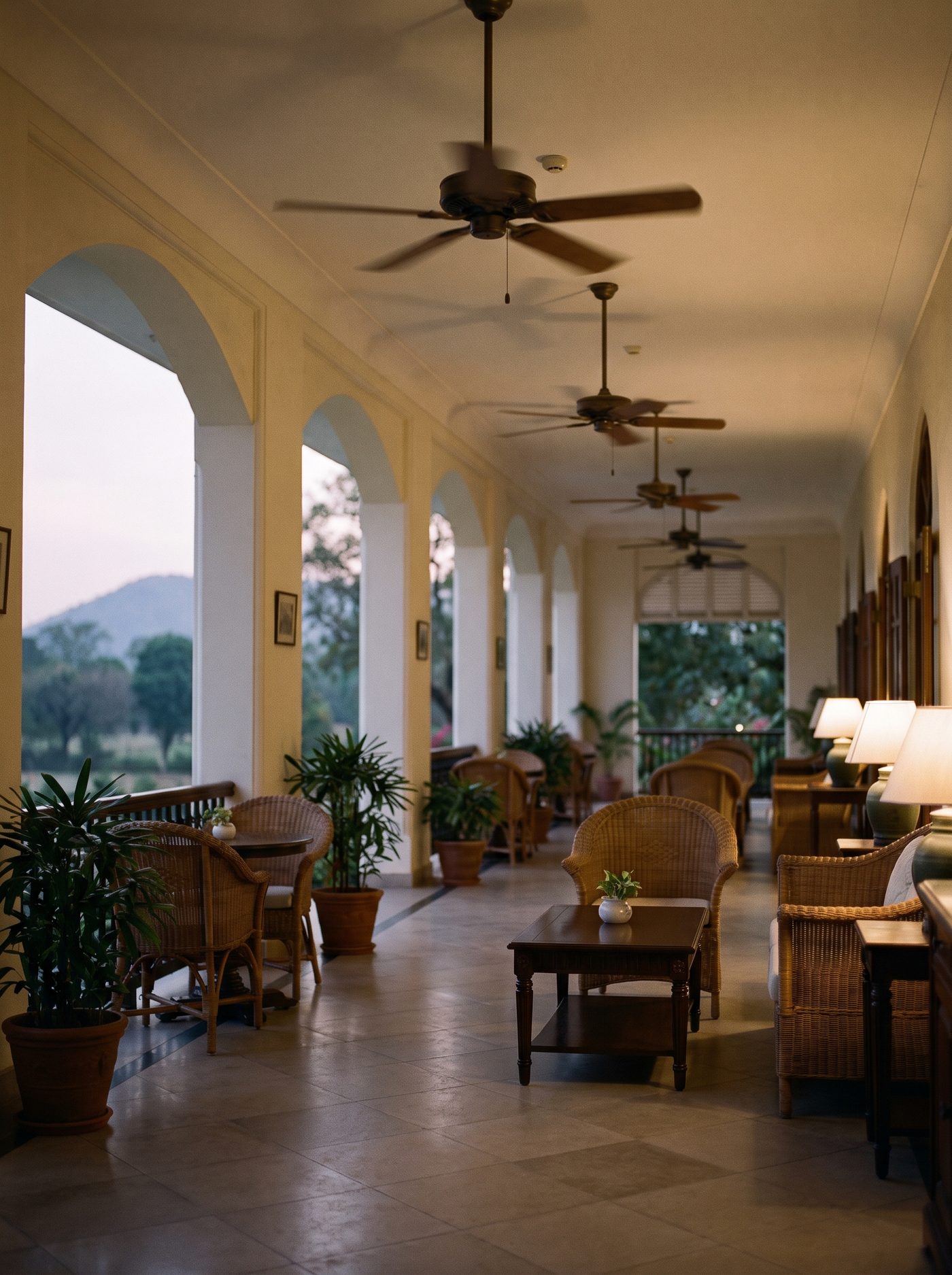 The clubhouse verandah at dusk, teak and lamplight